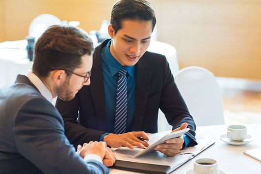 Two professionals discussing IT certifications at a meeting table.