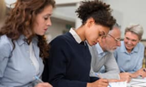 Group of students studying together with a mentor, focusing on IT certifications.