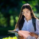 IT certification student reading outdoors.