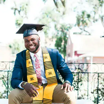 Happy graduate in cap and gown celebrating success outdoors.