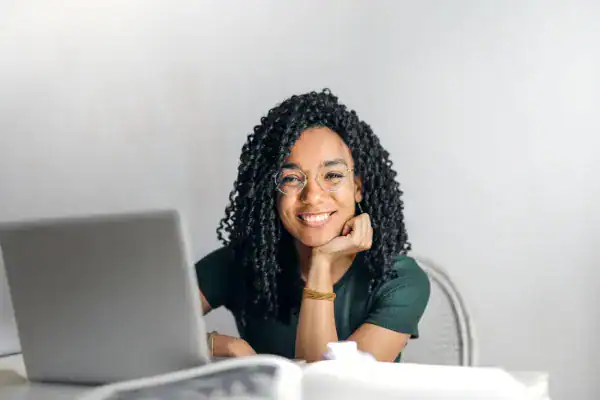 Woman smiling at laptop promoting IT certification courses.