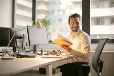 Man working at desk with computer and books in modern office.
