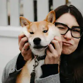 Woman with glasses hugging a happy dog, symbolizing trust and connection.