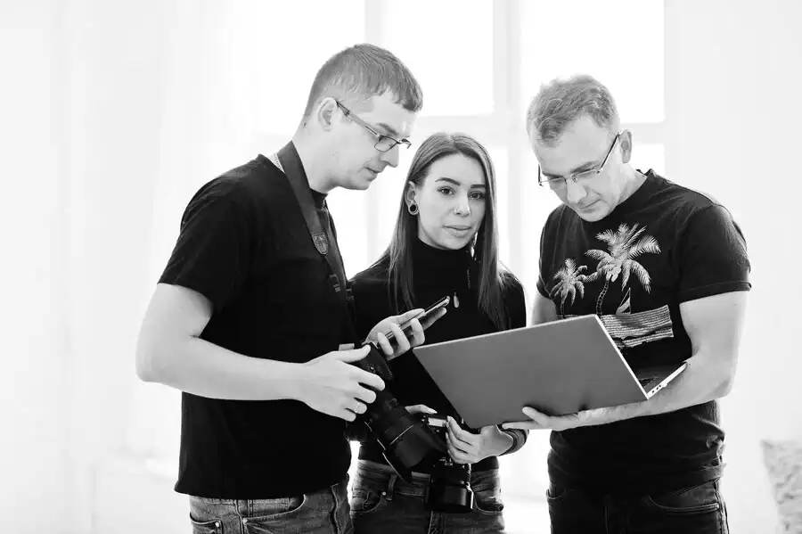 Group of three young professionals discussing IT certification materials indoors.