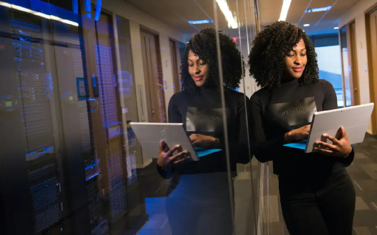 Woman in a data center holding a tablet, focusing on cybersecurity training.