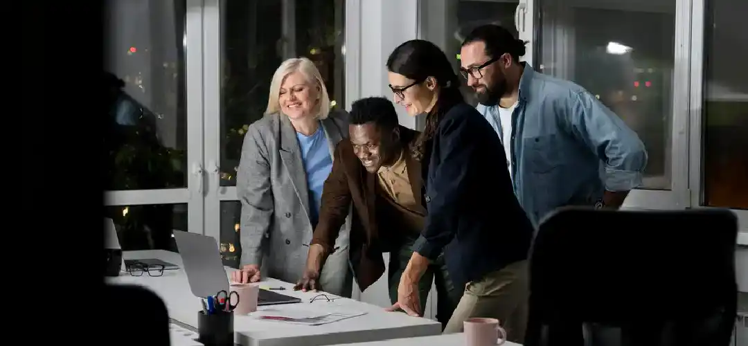 Team working together on a project at a desk with a computer.