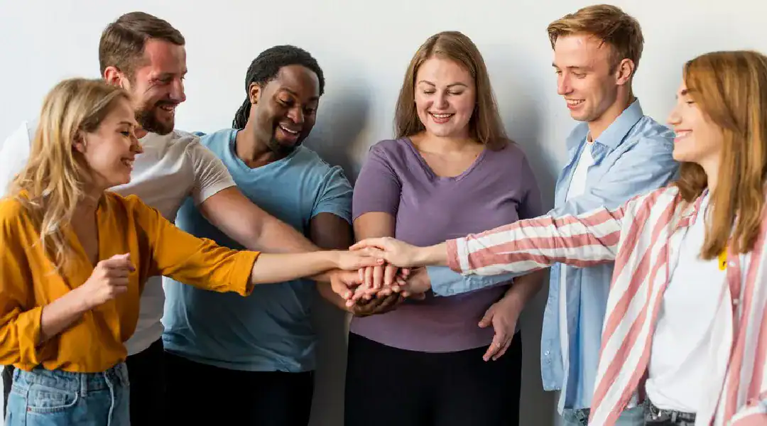 Group of diverse professionals joining hands in a team-building gesture.