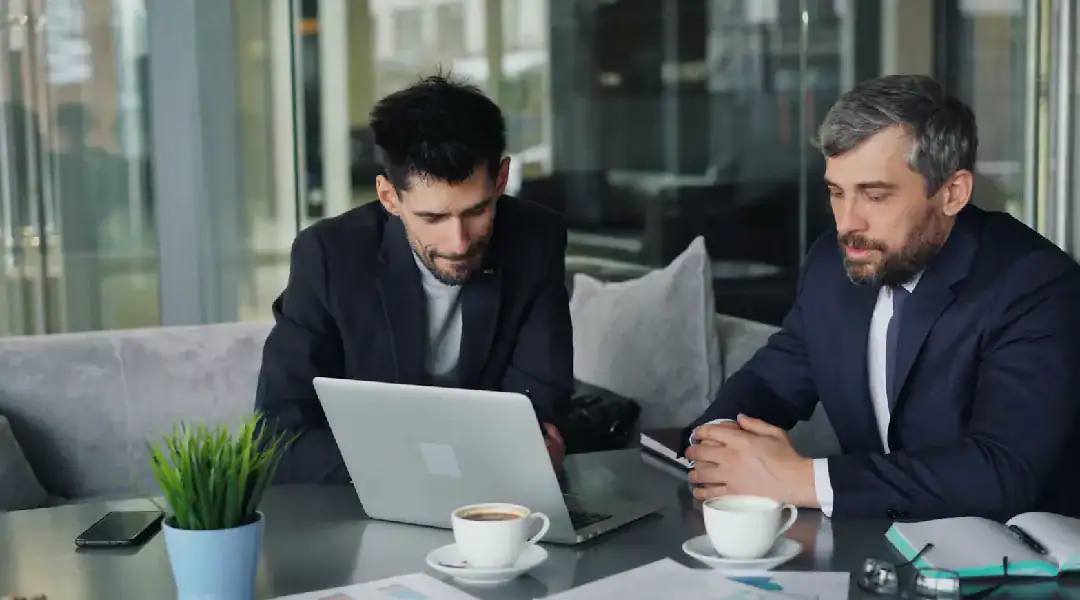Two professionals discussing IT certifications at a modern office table.
