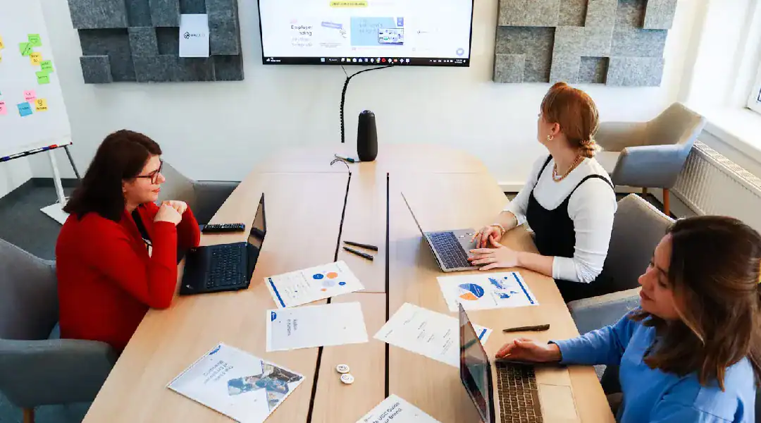 Business meeting with three women discussing IT certifications at a conference table.