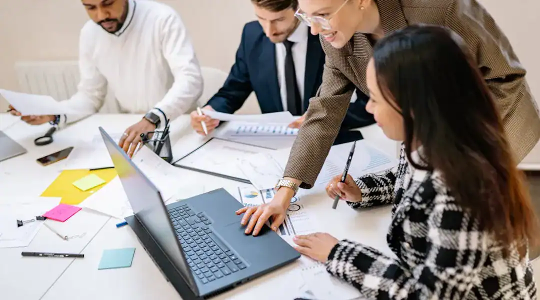 Group of professionals collaborating on a laptop for IT certification success.