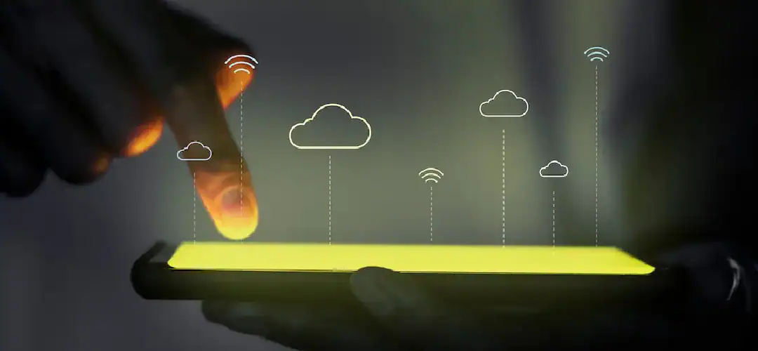 Person tapping a smartphone with cloud icons and Wi-Fi signals above it.