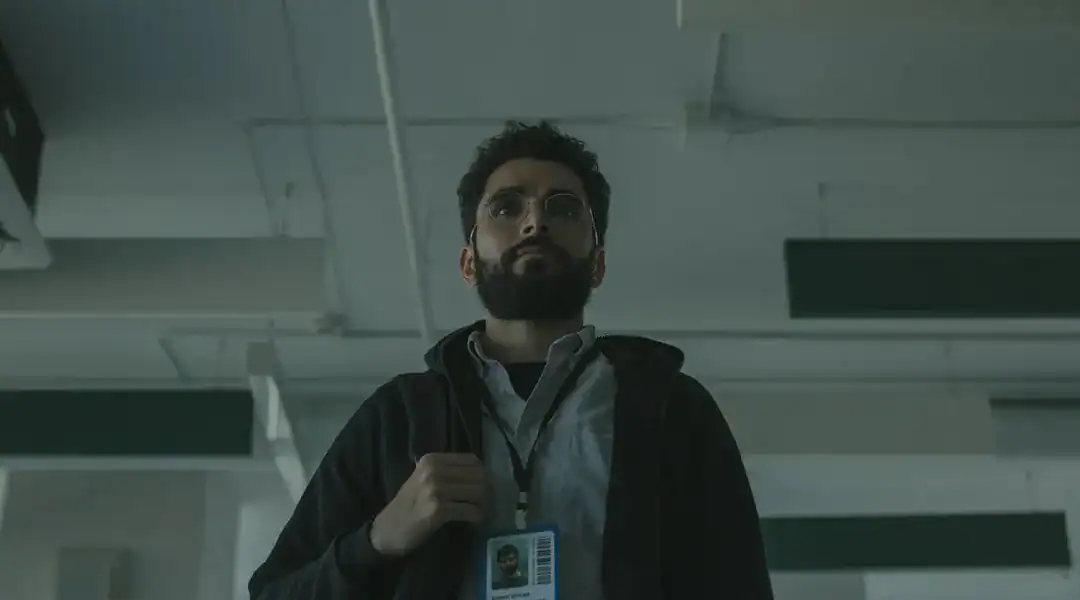 Man with ID badge in a modern office setting, focused and professional.