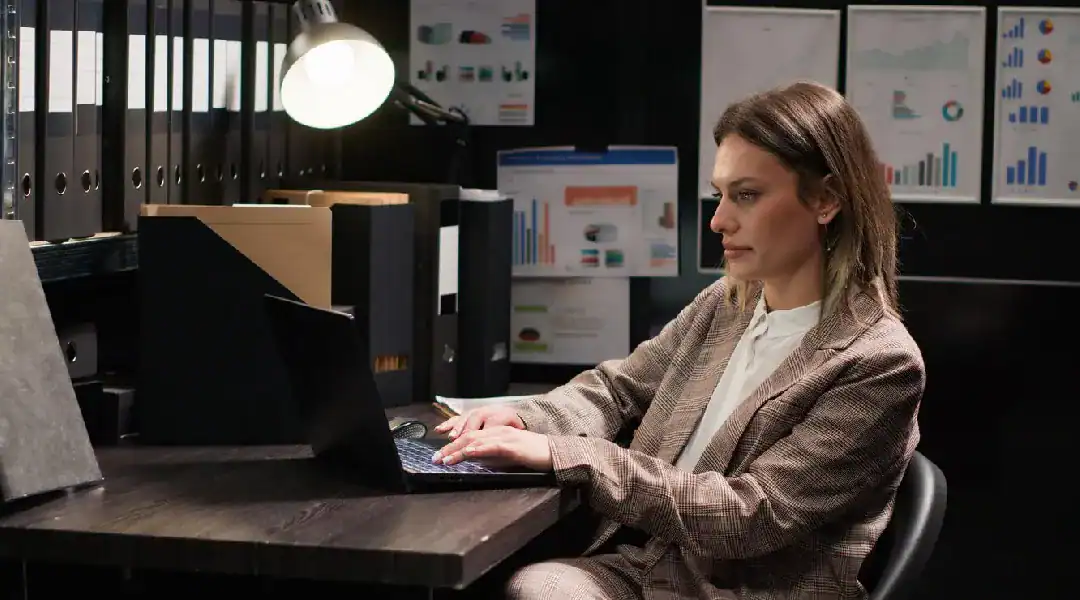 Woman working on cybersecurity analysis at her desk in an office.