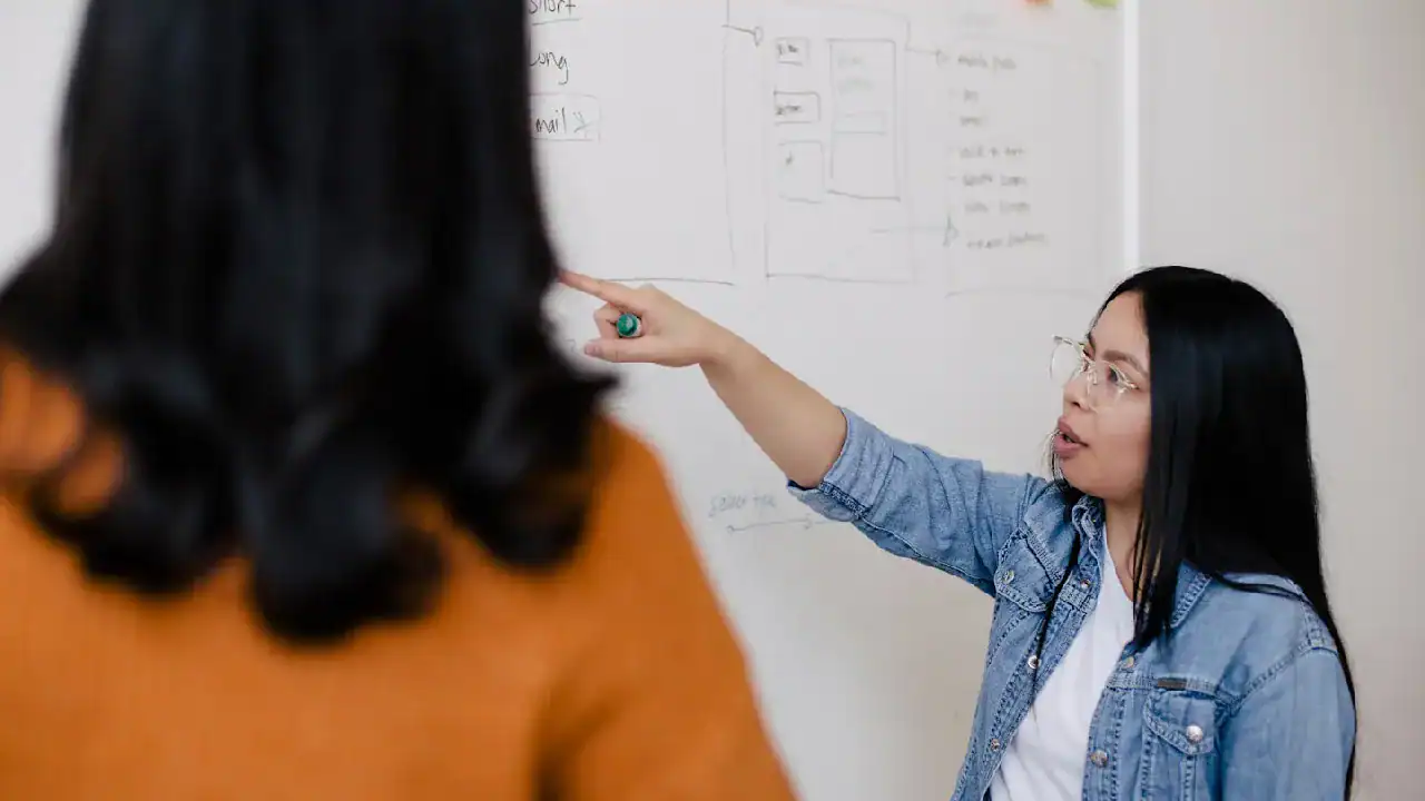 Woman explaining cloud networking concepts on whiteboard.