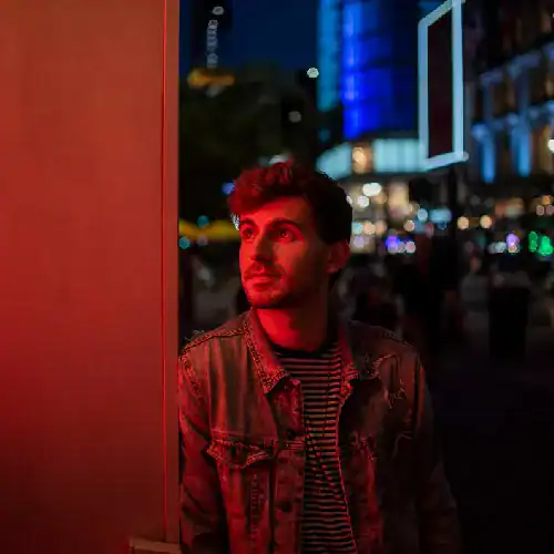 Young man at night in city with neon lights, representing cloud technology innovation.