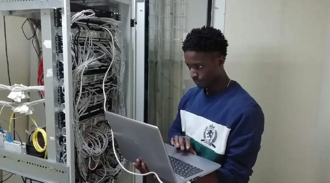 Technician working on server hardware with a laptop in a data center.