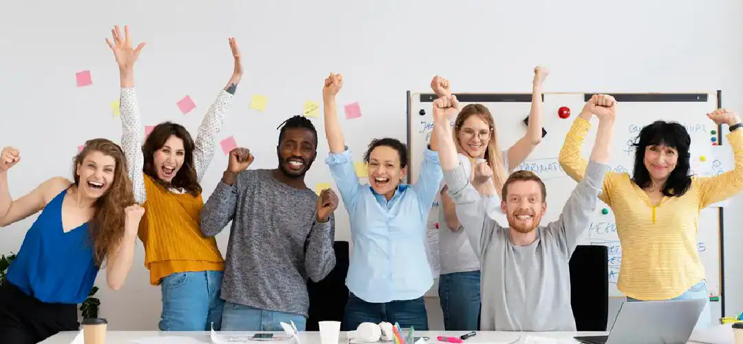 Group of diverse professionals celebrating success with raised hands.