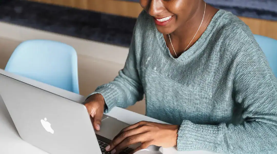 Smiling woman studying on laptop for MS-900 cloud certification exam.