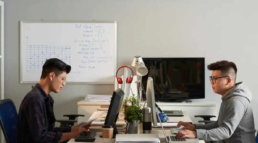 Two young men studying cloud computing certifications at a desk.