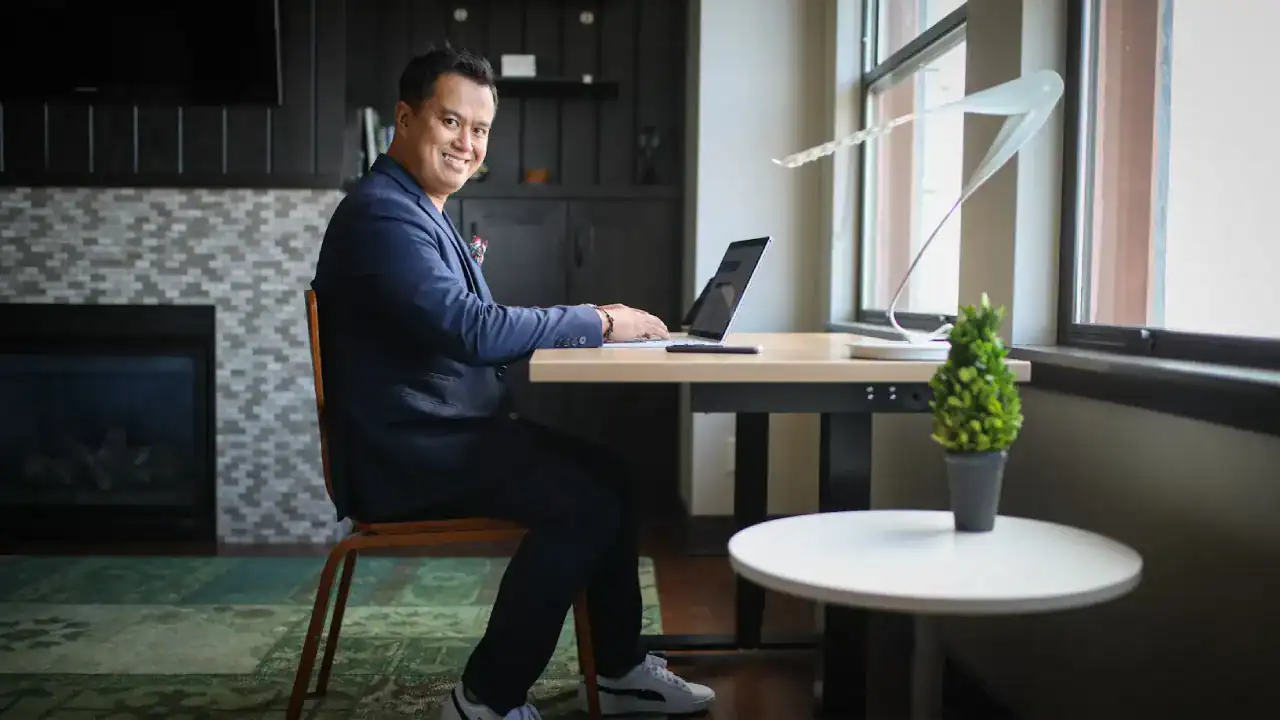 Smiling professional working on a laptop in a modern office setting.