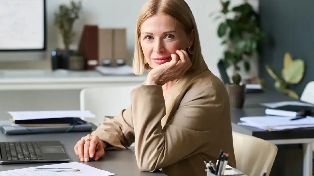 Woman working at desk with computer, representing IT certification success.