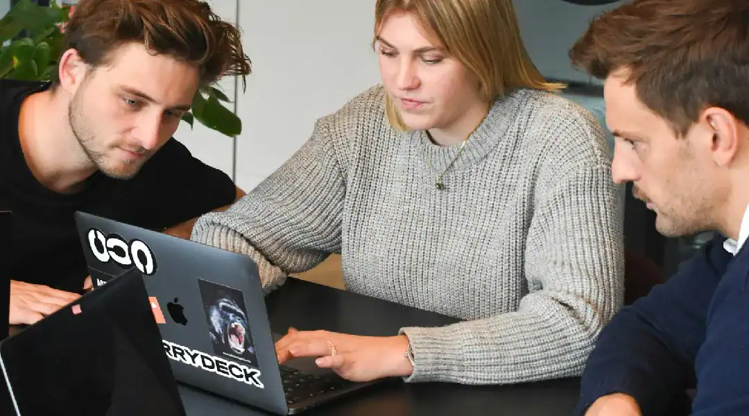 Group of professionals discussing data certification at a laptop.