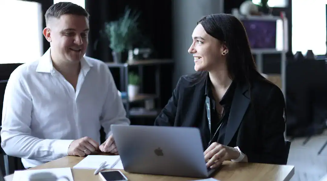 Two professionals discussing data certification at a modern office desk.