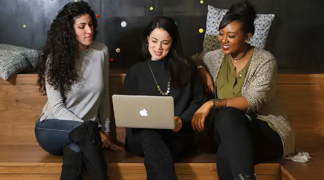 Women collaborating on a laptop, learning cloud technology together.