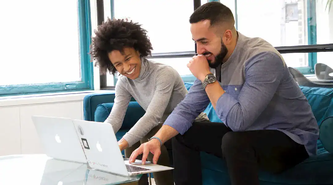 Two professionals collaborating on a laptop, exploring IT certification options.