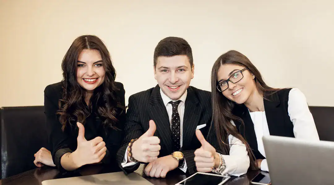 Group of professionals smiling and giving thumbs up in a business meeting.