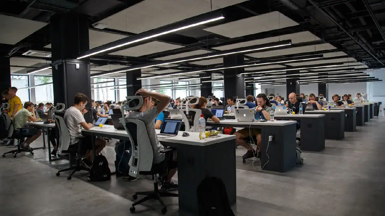 Modern open-plan office with employees working on computers in a tech company.