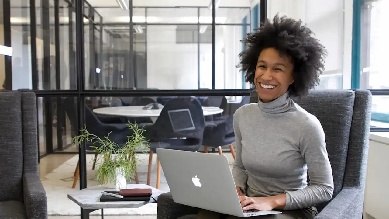 Young woman working on a MacBook in a modern office setting.
