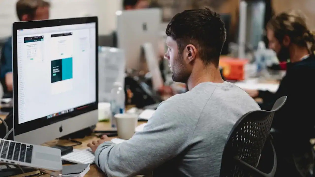 Young man working on a computer with Kubernetes certification content on screen.