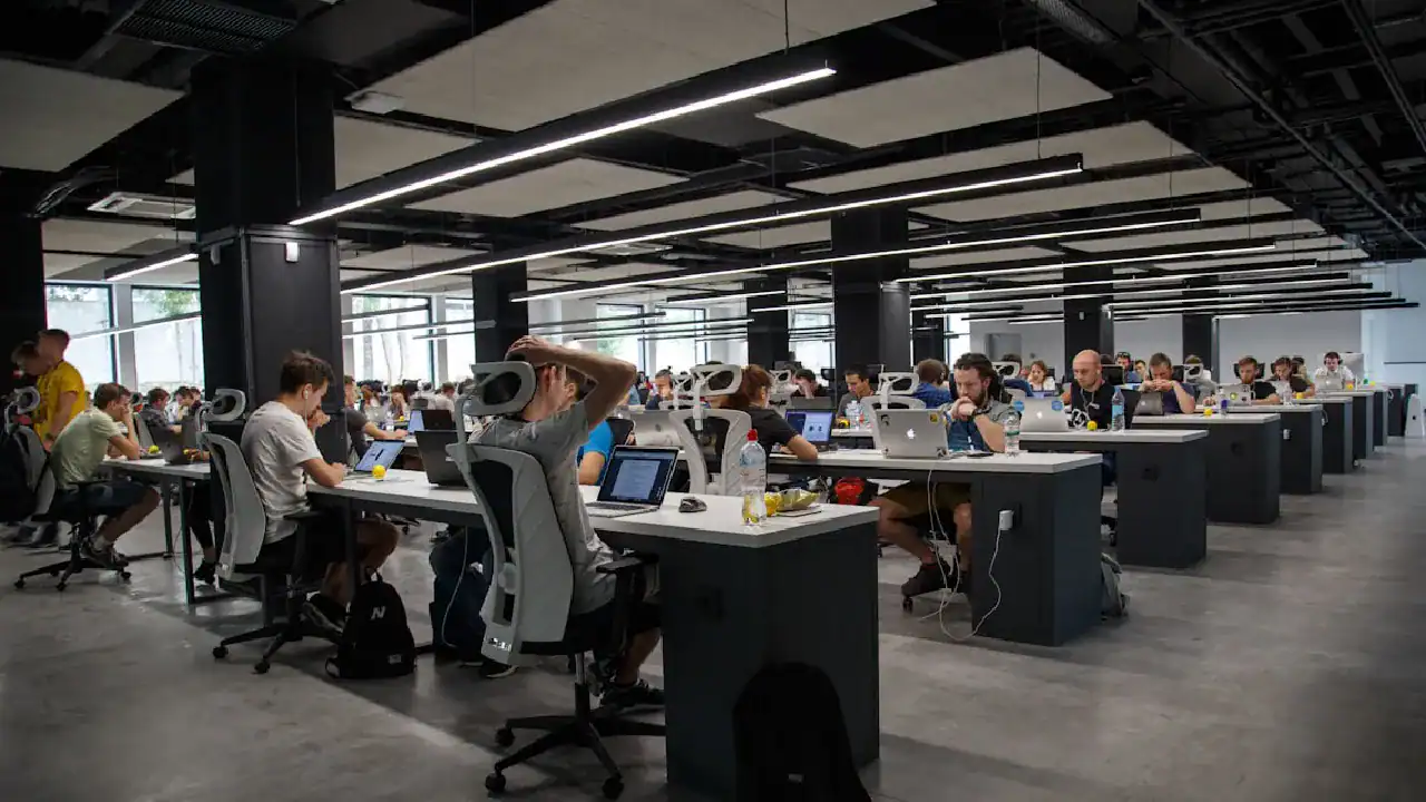 Students working on laptops in a modern computer lab for IT certification prep.