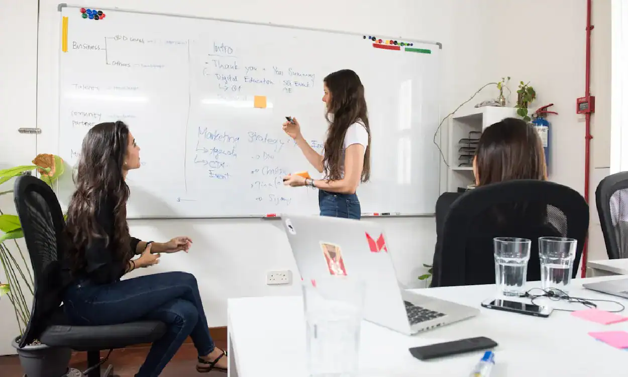 Women in a training session discussing machine learning concepts on whiteboard.