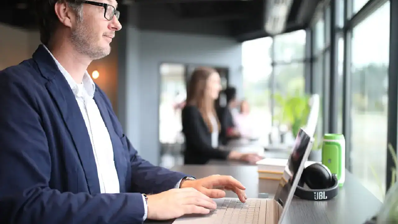 Fortinet NSE 6 network security professional working on a laptop in a modern office.