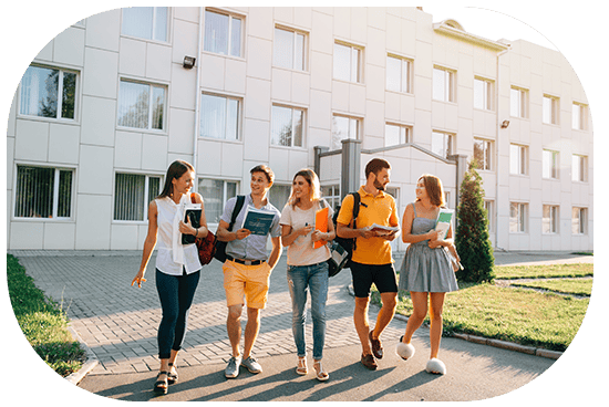 Prime Technologies students walking outside campus with books and backpacks.